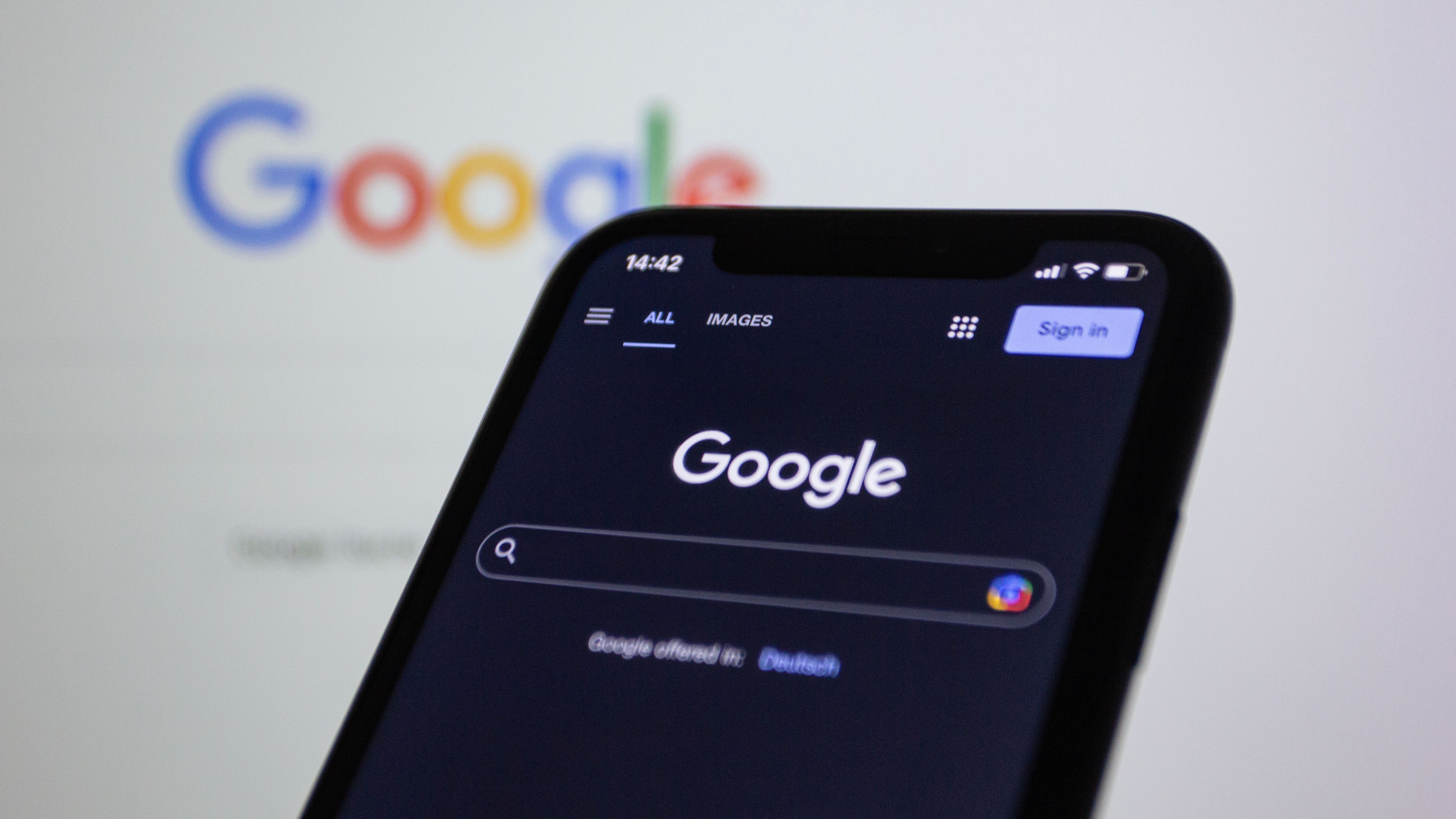 Smartphone screen showing a Google search in dark mode with the Google logo behind it