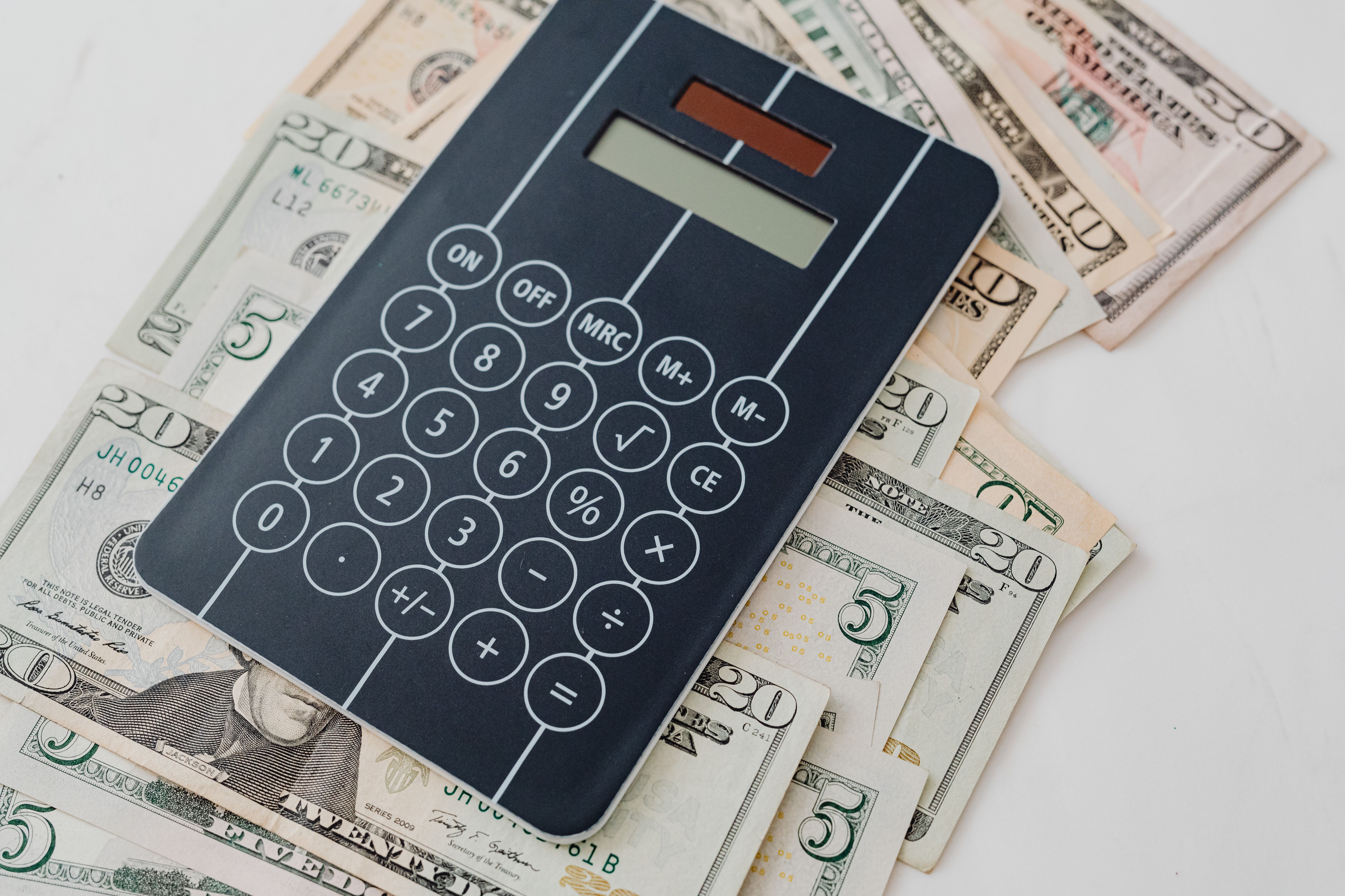 Calculator resting on US dollar bills symbolizing private jet charter costs