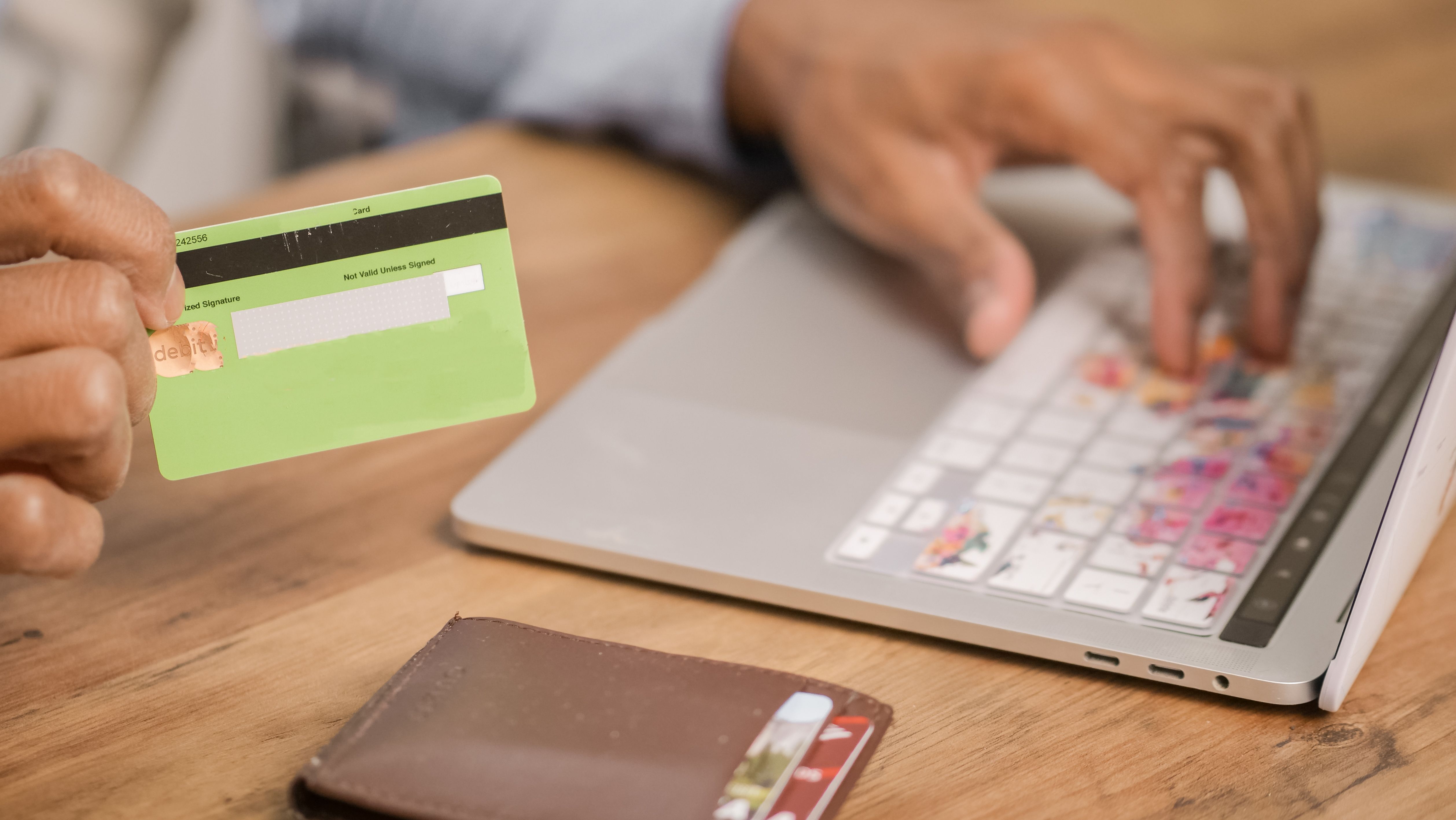 Customer completing an online transaction with a credit card beside a laptop