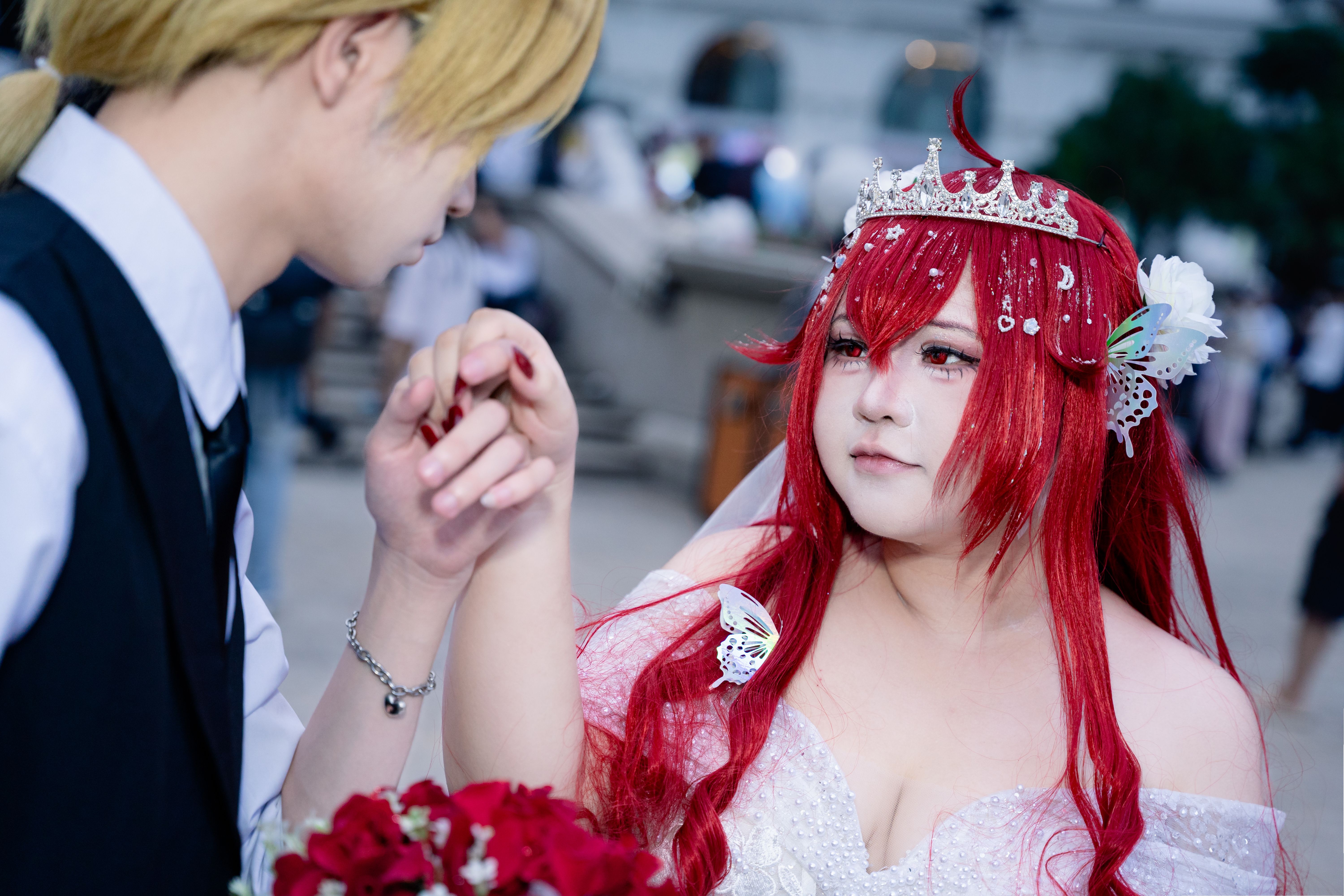Cosplay couple in imaginative attire sharing a tender moment at an outdoor event.