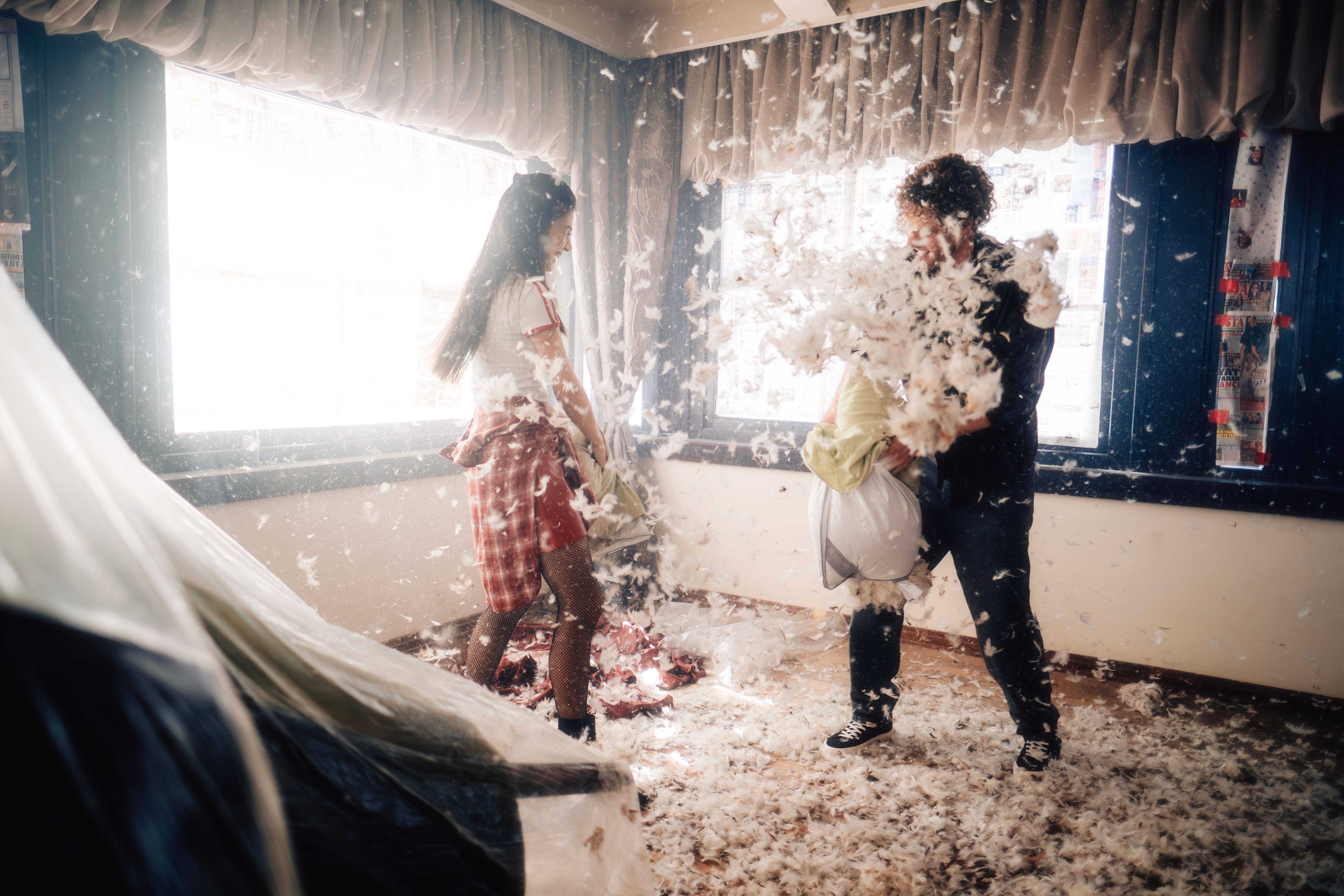 Two adults having a playful pillow fight at home, capturing spontaneity and fun in a relationship.
